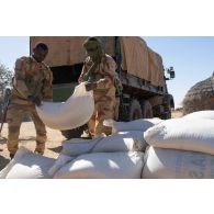 Des gardes nationaux nigériens déchargent du mil depuis un camion GBC-180 à Dougou Saro, au Niger.