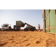 Des soldats du 121e régiment du train (RT) chargent des containers à bord d'un semi-remorque au moyen d'un chariot Manitou sur la plateforme logistique de PK 11, au Niger.