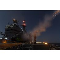 Des marins tirent une fusée éclairante depuis le pont d'envol du porte-hélicoptères amphibie (PHA) Tonnerre, en mer Méditerranée.