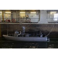 Un soldat britannique des Royal marines garde le bord de son zodiac dans le radier du porte-hélicoptères amphibie (PHA) Tonnerre en mer Méditerranée.