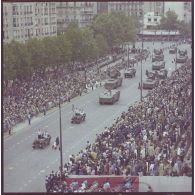 Vue aérienne du défilé motorisé. Passage du drapeau et sa garde à bord d'une Jeep de type Hotchkiss M-201 et de véhicules d'acquisition radar et de désignation d'objectifs et de tir avec radar de poursuite du système d'arme sol-air Crotale de l'armée de l'air de la base aérienne (BA) 118 de Mont-de-Marsan, lors de la cérémonie du 14 juillet 1977.