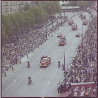 Vue aérienne du défilé motorisé. Passage du drapeau et sa garde et de véhicules et motards de la brigade des sapeurs-pompiers de Paris (BSPP), lors de la cérémonie du 14 juillet 1977.