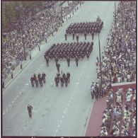 Vue aérienne du défilé à pied. Passage des drapeaux et leur garde des écoles du service de santé (ESSA), lors de la cérémonie du 14 juillet 1977.