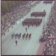 Vue aérienne du défilé à pied. Passage des drapeaux et leur garde de l'école spéciale militaire (ESM) de Saint-Cyr et de l'école militaire interarmées (EMIA), lors de la cérémonie du 14 juillet 1977.