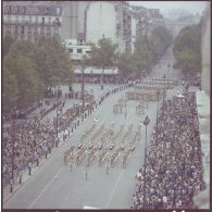 Vue aérienne du défilé à pied. Passage des pionniers de la Légion étrangère suivis de la musique de la Légion étrangère (MLE), et des drapeaux et leur garde des unités de la Légion étrangère, le 1er régiment étranger (1er RE), le 2e régiment étranger (2e RE), le 1er régiment étranger de cavalerie (1er REC) et le 2e régiment étranger parachutiste (2e REP), lors de la cérémonie du 14 juillet 1977.