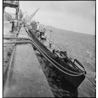 Le sous-marin des Forces navales françaises libres la Minerve est accosté à quai par tribord dans un port.