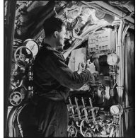 Sous-marinier de quart manoeuvrant, au cours d'un exercice, le tableau de commande des purges des ballasts du sous-marin des Forces navales françaises libres (FNFL) la Minerve.