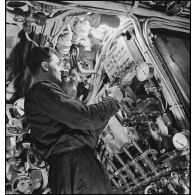 Sous-marinier de quart manoeuvrant, au cours d'un exercice, le tableau de commande des purges des ballasts du sous-marin des Forces navales françaises libres (FNFL) la Minerve.