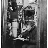 L'opérateur radio du sous-marin des FNFL (Forces navales françaises libres) la Minerve envoie ou réceptionne des messages depuis le poste central radio, au cours d'un exercice.