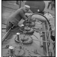 Un soldat positionne un tuyau dans une citerne de camion. Il est photographié en légère plongée.