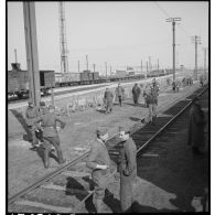 En gare de Trappes plan général d'une voie ferrée près de laquelle des soldats debout attendent.