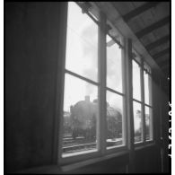 En gare de Trappes une locomotive est photographiée au travers de la fenêtre d'un baraquement.