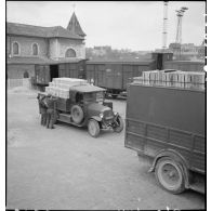 Plan général d'une opération de transbordement : des camions chargés de produits alimentaires sont garés près d'un train de marchandises.