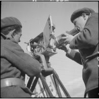 Plan américain d'un opérateur de prise de vue et son aide qui changent la pellicule de la caméra au col des Rochilles (limite entre la Savoie et les Hautes-Alpes, à proximité du col du Galibier).