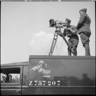 Un opérateur de prise de vue du SCA et son aide sont photographiés sur le toit du camion SCA immatriculé Z757207 en contre-plongée lors d'un tournage  au fort du Télegraphe, sous le col du Galibier.