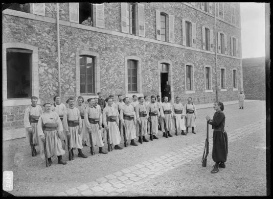 Les zouaves alignés, leurs fusils à leurs pieds devant la caserne. [légende d'origine]