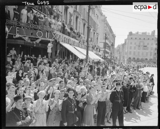 La population marseillaise acclame les troupes lors du défilé, à l'angle de la Canebière et du quai des Belges.