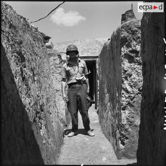 Portrait du caporal-chef Pierre Schoendoerffer, caméraman du Service cinématographique des armées, dans une tranchée de Diên Biên Phu.