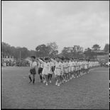 Défilé de jeunes athlètes des écoles chrétiennes faisant le salut olympique lors d'une grande réunion des élèves catholiques au stade Mangin.