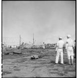 Des marins américains de la MP (police militaire ou military police) regardent un navire pétrolier incendié dans le port d'Alger.