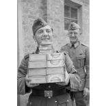 Un caporal de l'armée de terre (Gefreiter) reçoit des cigares et cigarettes de l'officier responsable du magasin d'approvisionnement.