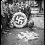 Trophées de guerre dans une rue de Belfort libéré : une couronne avec la croix gammée (le swastika nazi), une sculpture de la croix de fer et un buste d'Hitler.