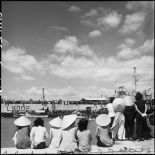 Sur le port, des Vietnamiennes observent l'embarquement de légionnaires quittant l'Indochine.
