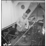 Un marin mécanicien huile des pièces dans la salle des machines du chalutier de la marine marchande Roche noire, réquisitionné par la Marine nationale.