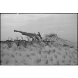 Canonniers servants d'un canon de 75 mm antiaérien camouflé, affecté à une batterie d'artillerie de défense côtière de la Marine nationale sur le littoral.