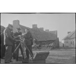 Caméramans du service cinématographique de la Marine (SCA/Marine) en tournage avec une caméra Debrie dans une cour de ferme.