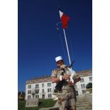 Le chien Scud, mascotte du 2e REI (régiment étranger d'infanterie), dans les bras d'un légionnaire en arme sur la place d'armes du quartier Colonel de Chabrières au pied du mât des couleurs.