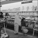 Une femme voilée et une enfant devant le rayon poupées d'un supermarché.