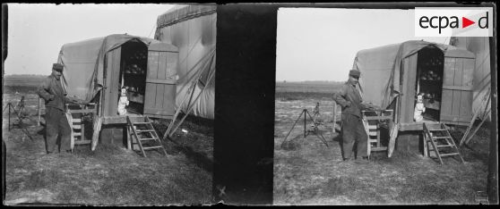 [Un soldat devant la baraque roulante contenant les munitions et un chien qui fait le beau dans l'encadrement de la porte].<br>
