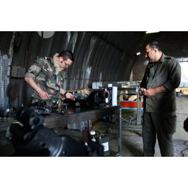ImagesDéfense - Un sergent-chef armurier (petaf) sur Mirage 2000 examine  des pièces mécaniques sur un établi sous un hangar de maintenance, en  présence d'un mécanicien qatari.
