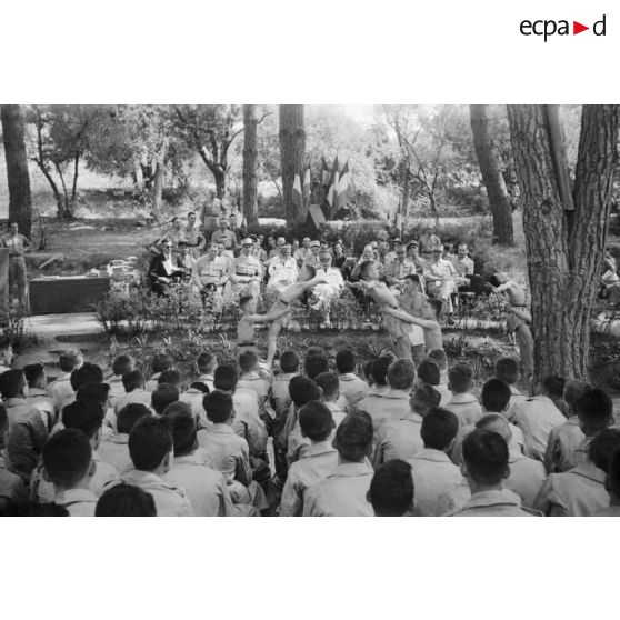 Des élèves de l'Ecole militaire préparatoire nord-africaine (EMPNA) d'Hammam Righa effectuent des figures acrobatiques sous le regard du général de corps d'armée Henry Martin, de personnalités civiles et militaires et des élèves de l'école, en plein air.