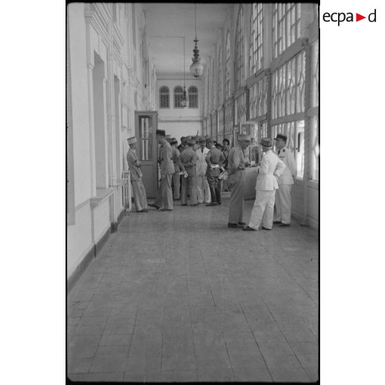 Le général de corps d'armée Henry Martin s'entretient avec des autorités militaires dans les couloirs de l'Ecole militaire préparatoire nord-africaine (EMPNA) d'Hammam Righa.