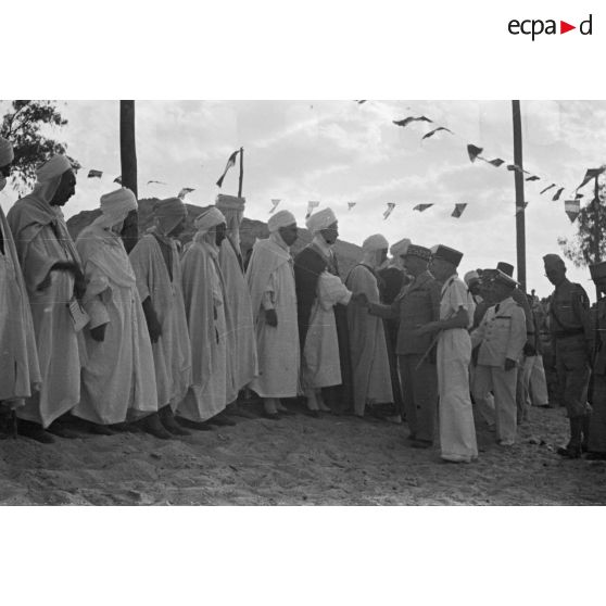 Le général de corps d'armée Henry Martin salue des autorités locales, accompagné d'autorités militaires.