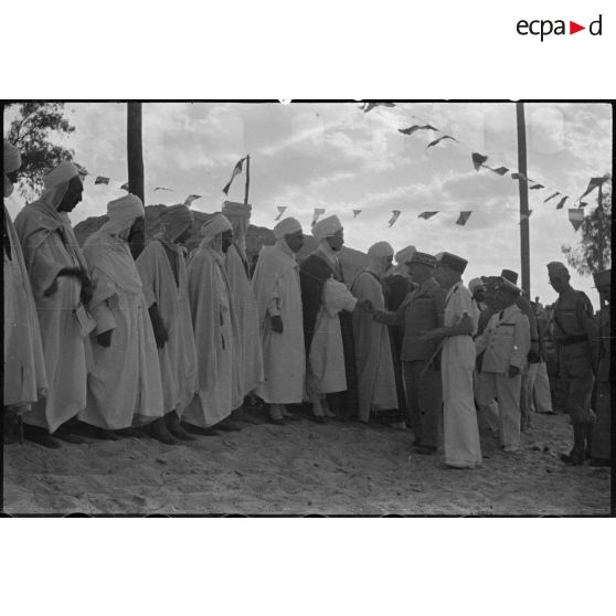 Le général de corps d'armée Henry Martin salue des autorités locales, accompagné d'autorités militaires.