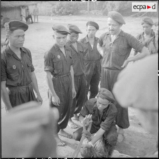 Des éléments de la section parachutiste Thaï de Lai Chau s'exercent au pliage de parachute sur les instructions du sergent moniteur Montfort.