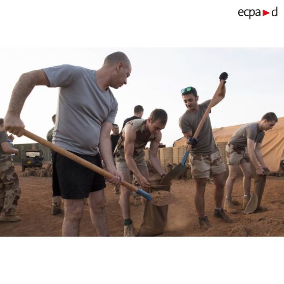 Des éléments de l'état-major remplissent des sacs à terre pour la consolidation des infrastructures du camp de Gao, au Mali.