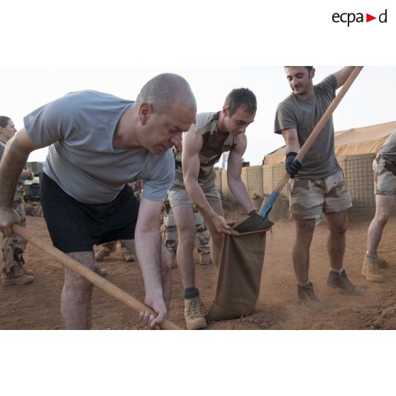 Des éléments de l'état-major remplissent des sacs à terre pour la consolidation des infrastructures du camp de Gao, au Mali.