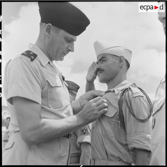 Lors de la passation de commandement au 4e RAC (régiment d'artillerie coloniale), le général de division Cogny, commandant les FTNV (forces terrestres du Nord-Vietnam), décore un tirailleur.