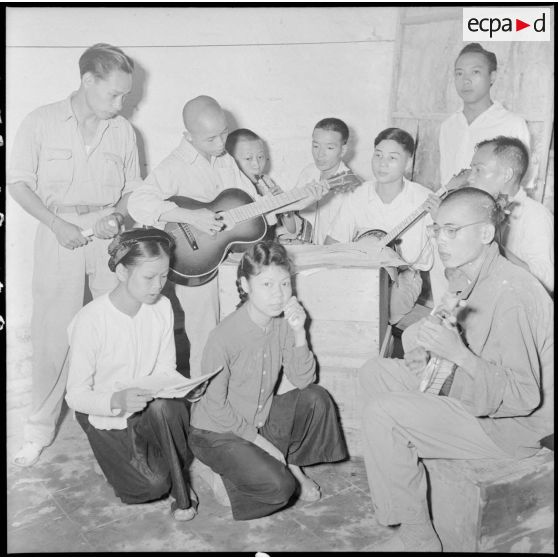 Des prisonniers d'un camp de PIM (prisonniers et internés militaires) jouent de la guitare en chantant.