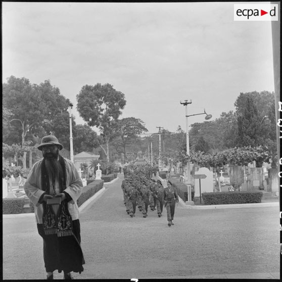 Convoi funéraire arrivant au cimetière militaire d'Hanoï lors des obsèques du médecin-capitaine Jean Raymond, en présence du prêtre et de différentes unités des TAPN (Troupes aéroportées parachutistes du Nord).