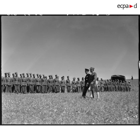 Le général de brigade Jean Breuillac passe en revue une troupe de tirailleurs algériens, sur un camp militaire.