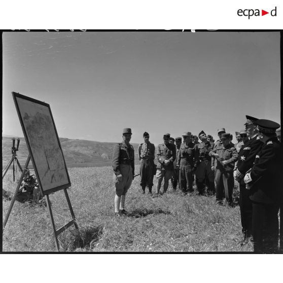 Le général de brigade Jean Breuillac échange avec des autorités militaires devant une carte de manoeuvres, sur un camp militaire.