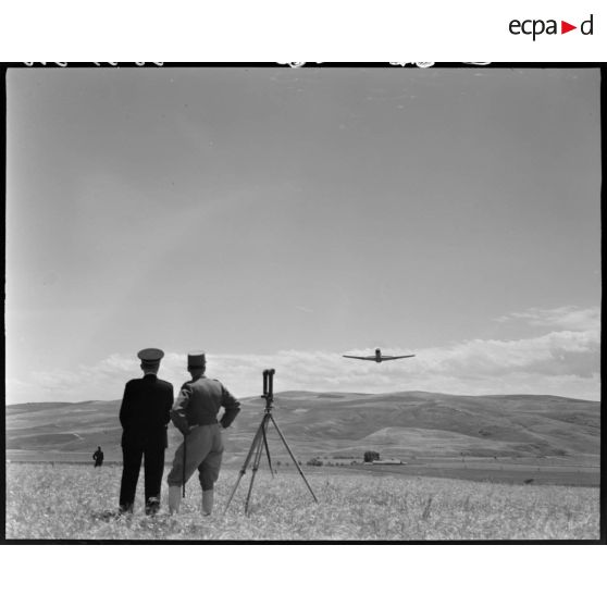 Le général de brigade Jean Breuillac, assisté du gouverneur général de l'Algérie, Yves Chataigneau, observe l'exercice de vol d'un avion.