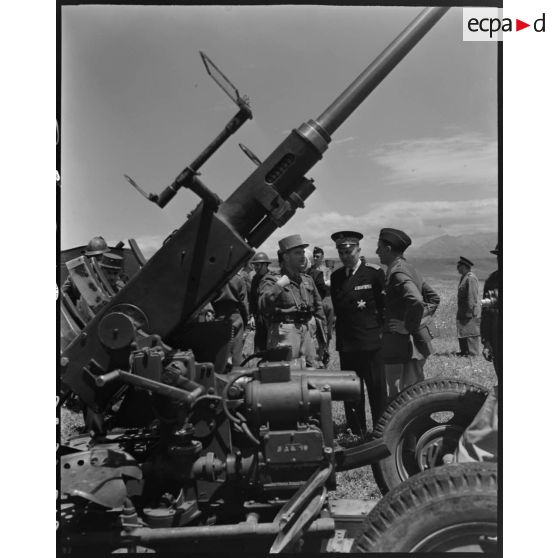Le général de brigade Jean Breuillac assiste au fonctionnement d'un canon anti-aérien, accompagné du gouverneur général de l'Algérie, Yves Chataigneau.<br>