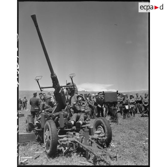 Le général de brigade Jean Breuillac assiste au fonctionnement d'un canon anti-aérien, accompagné d'autorités militaires.
