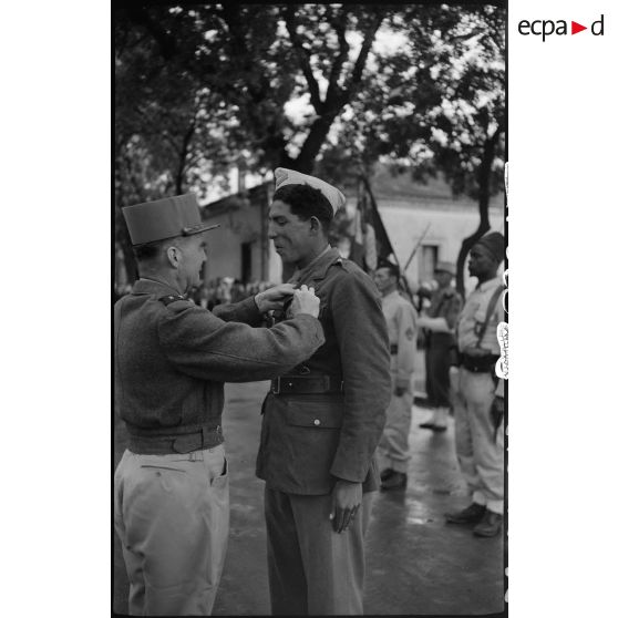 Défilés d'unités militaires et cérémonie de remise de décorations, sous la direction du général de brigade Jean Breuillac, devant la mairie de Aïn Bessem.